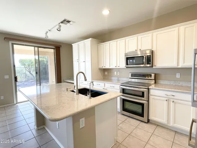 a kitchen with kitchen island granite countertop a stove sink and microwave
