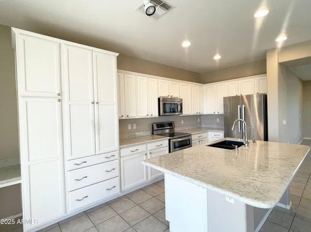 a kitchen with white cabinets and stainless steel appliances
