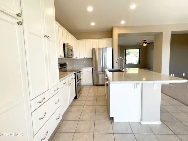 a large kitchen with stainless steel appliances kitchen island granite countertop a refrigerator and a sink