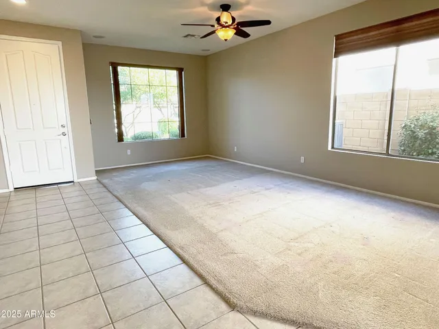 an empty room with windows and chandelier fan