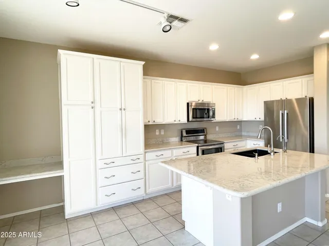 a kitchen with stainless steel appliances granite countertop a refrigerator and a stove top oven