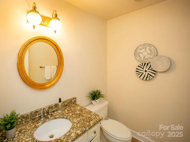 a bathroom with a granite countertop toilet sink mirror and vanity