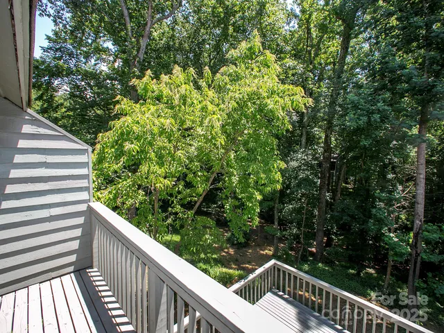 a balcony with wooden floor and trees in the back
