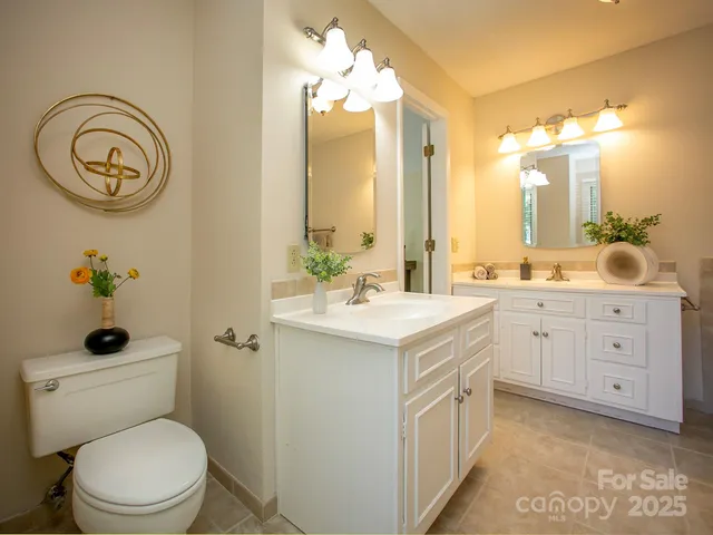 a spacious bathroom with a double vanity sink a toilet and a mirror