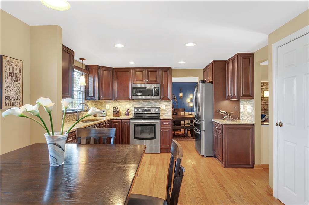 111 Hidden Valley Road Monroeville, PA 15146 - Photo 9 of 25 a kitchen with refrigerator a stove top oven a sink dishwasher and wooden cabinets with wooden floor