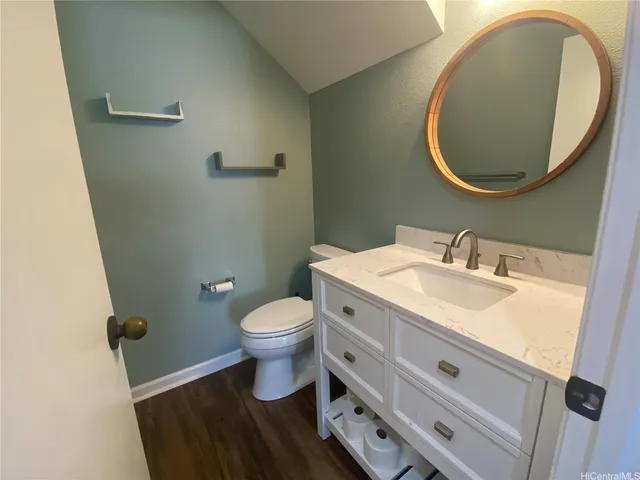 a bathroom with a granite countertop toilet sink and mirror