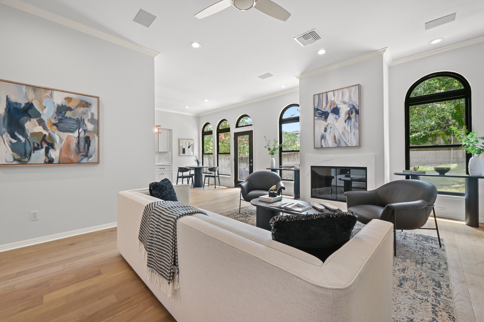 1107 Bowie Road Austin, TX 78733 - Photo 11 of 40 Light-filled living room featuring elegant arched windows, a modern fireplace, and rich hardwood flooring throughout.