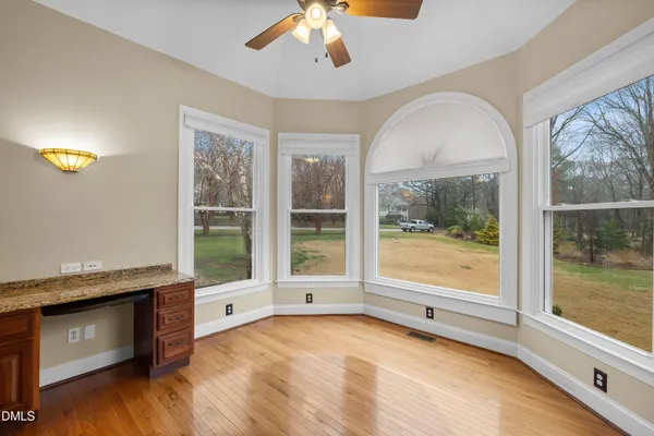 an empty room with wooden floor chandelier fan and windows