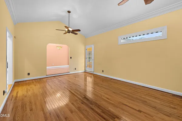 a view of an empty room with a window and wooden floor