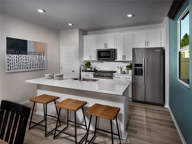 a kitchen with stainless steel appliances a kitchen island hardwood floor sink and stove
