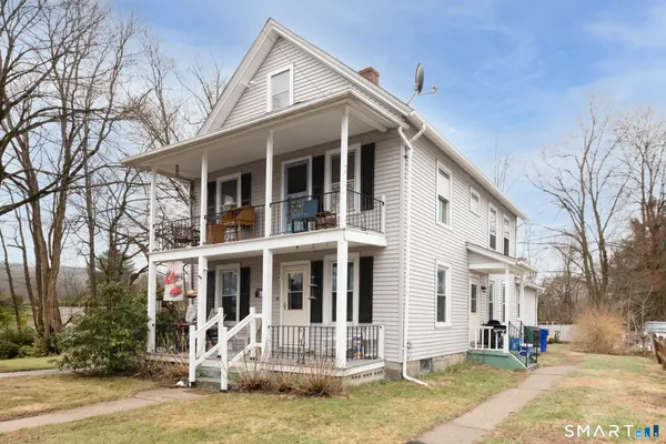 a view of a white house with large windows next to a road