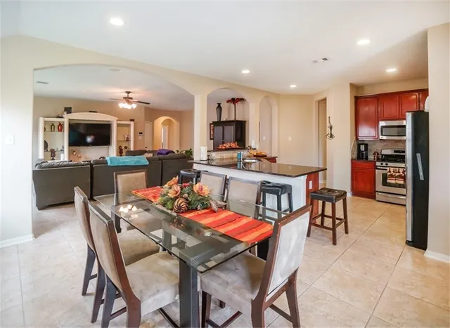 a dining hall with stainless steel appliances kitchen island granite countertop a dining table and chairs
