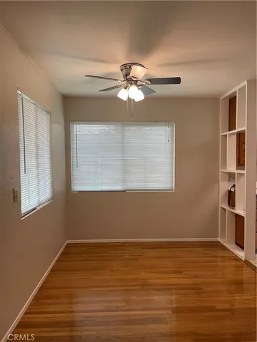 a view of a room with wooden floor and a ceiling fan