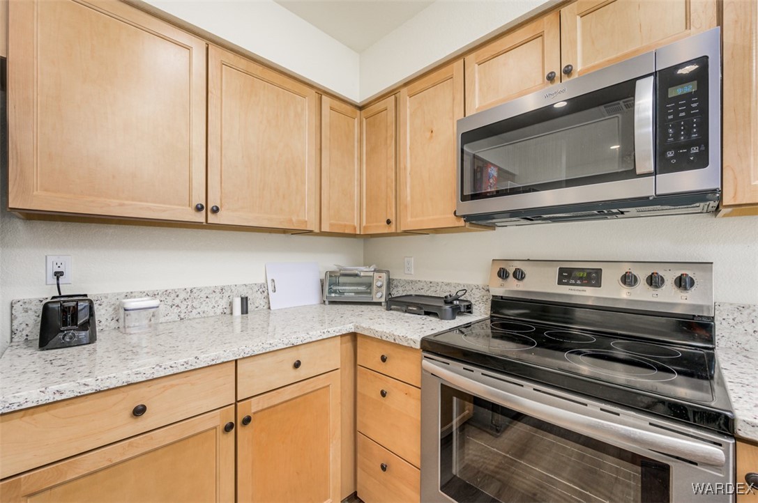 2004 Mesquite Lane, Unit 304 Laughlin, NV 89029 - Photo 7 of 36 a kitchen with stainless steel appliances granite countertop a sink a stove a microwave and cabinets