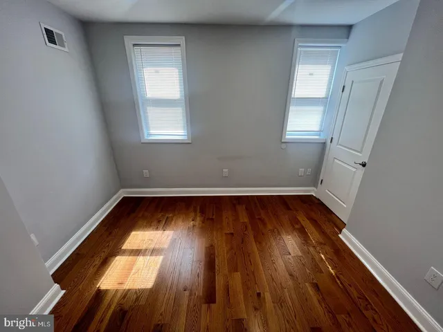 a view of empty room with wooden floor