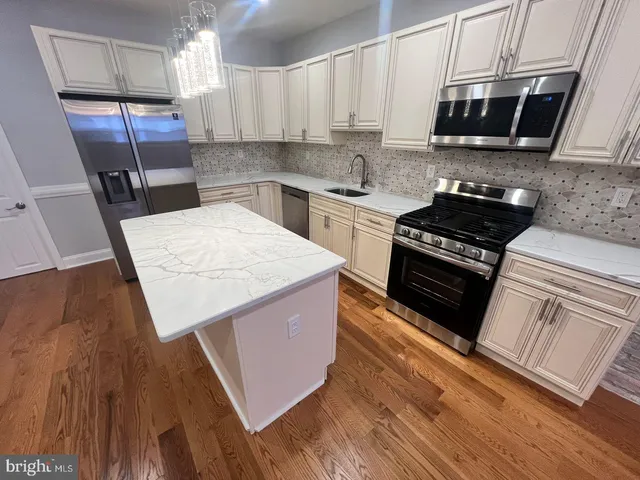 a kitchen with stainless steel appliances a stove a sink a microwave a refrigerator and cabinets