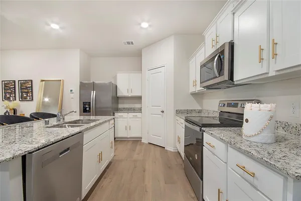 a kitchen with stainless steel appliances granite countertop a sink stove oven and white cabinets