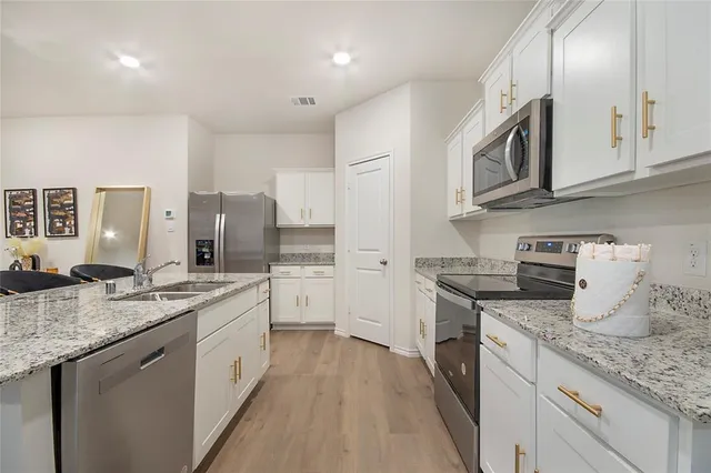 a kitchen with stainless steel appliances granite countertop a sink stove oven and white cabinets