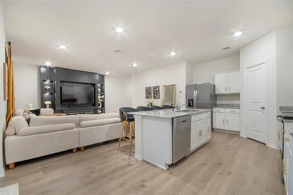a living room with stainless steel appliances furniture and a flat screen tv
