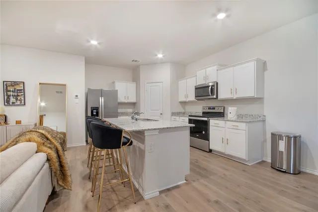 a kitchen with stainless steel appliances granite countertop a sink a stove a refrigerator and a microwave