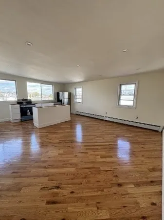 a view of a kitchen with kitchen island a sink wooden floor and a large window