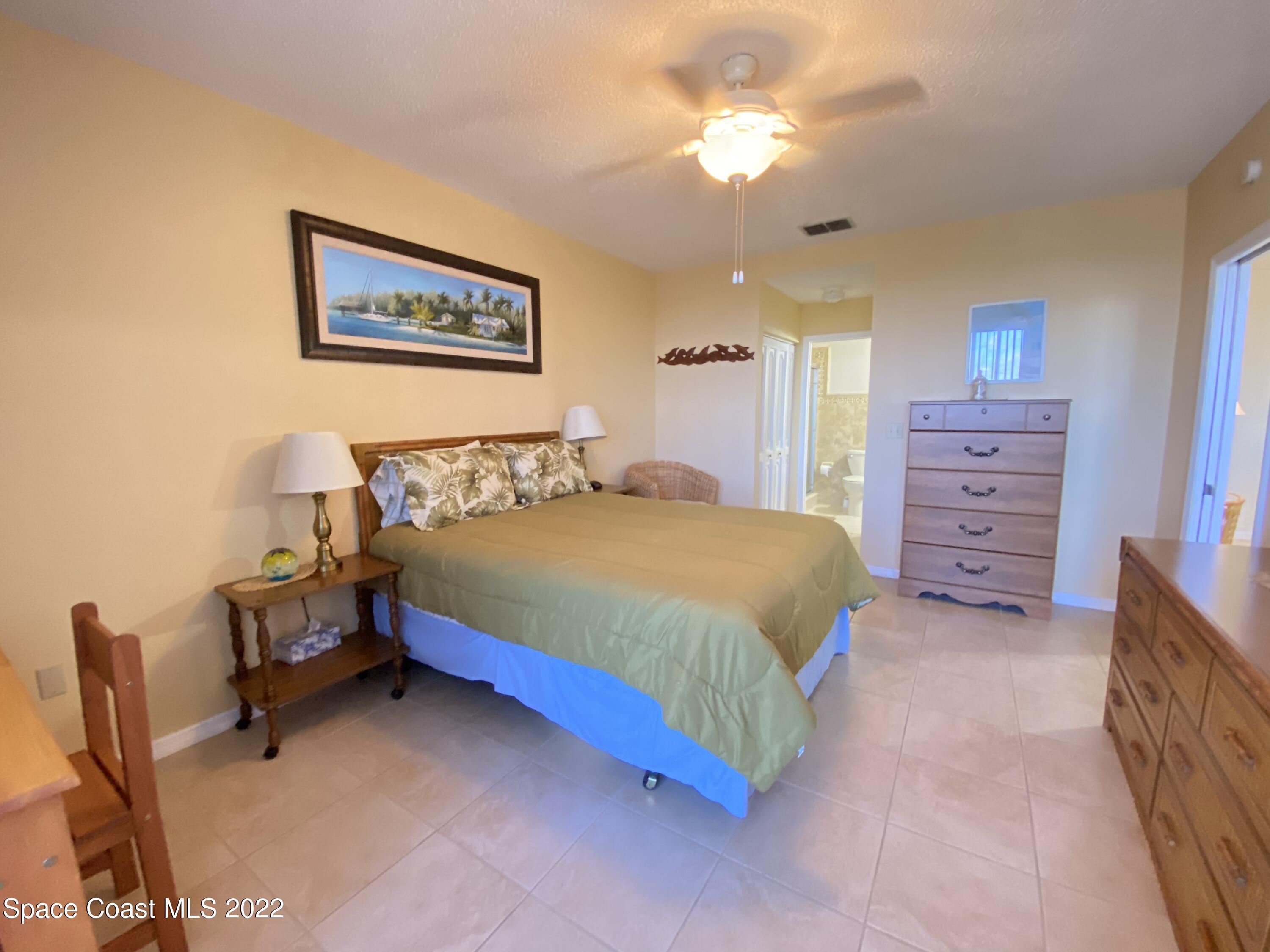 333 North Atlantic Avenue, Unit 305 Cocoa Beach, FL 32931 - Photo 11 of 21 a bedroom with a bed and a chandelier