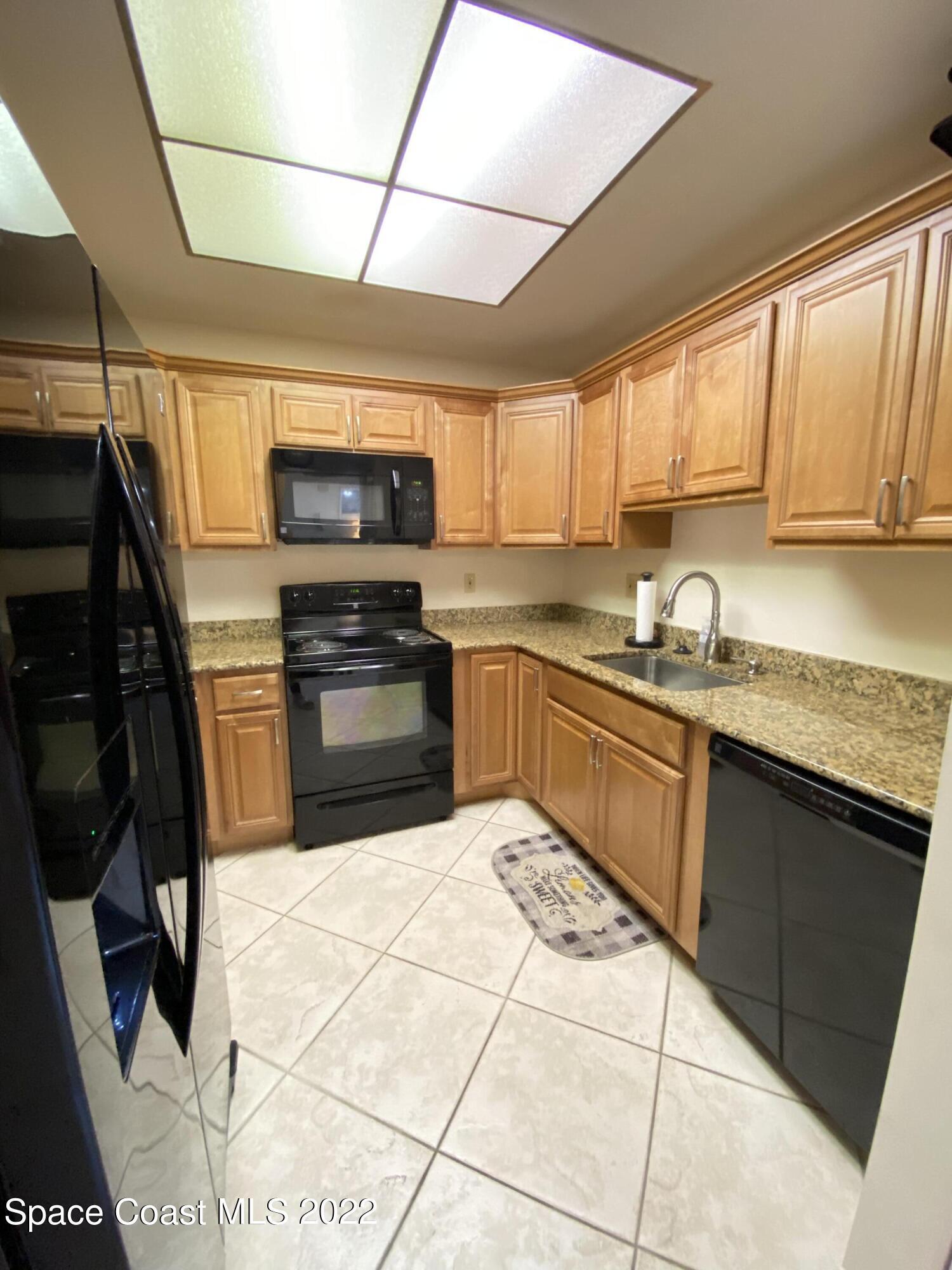 333 North Atlantic Avenue, Unit 305 Cocoa Beach, FL 32931 - Photo 9 of 21 a kitchen with stainless steel appliances granite countertop a sink a stove a microwave a sink and cabinets