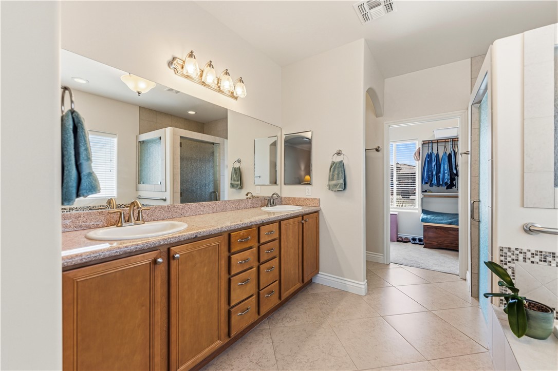 3315 Rainbow Mine Road Kingman, AZ 86401 - Photo 21 of 54 The bathroom features a double vanity with wooden cabinetry, a large mirror, and tiled flooring