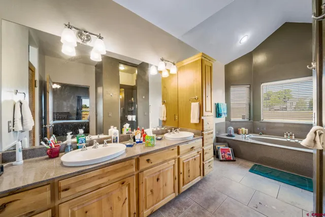 a spacious bathroom with a double vanity sink large mirror and a bathtub