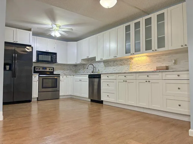 a kitchen with stainless steel appliances granite countertop white cabinets a refrigerator a sink a stove and white cabinets
