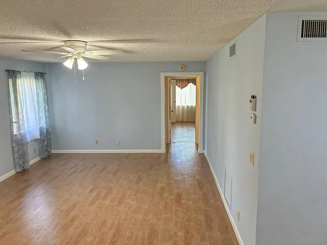 a view of an empty room with a window and wooden floor