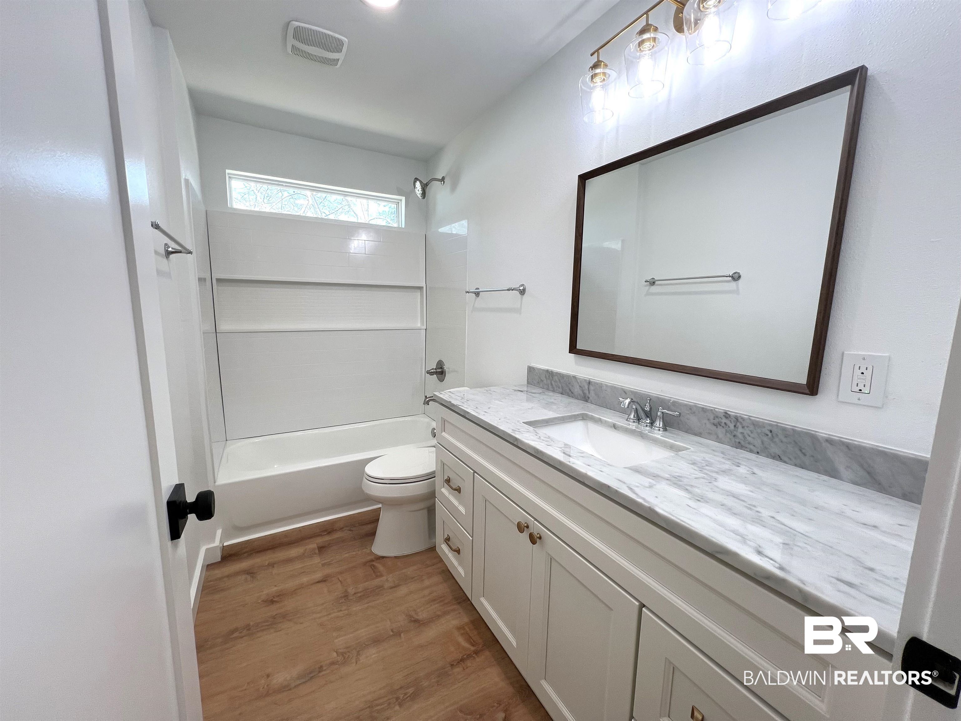 102 Earl Street Brewton, AL 36426 - Photo 14 of 27 Full bathroom with toilet, wood finished floors, vanity, bathing tub / shower combination, and visible vents
