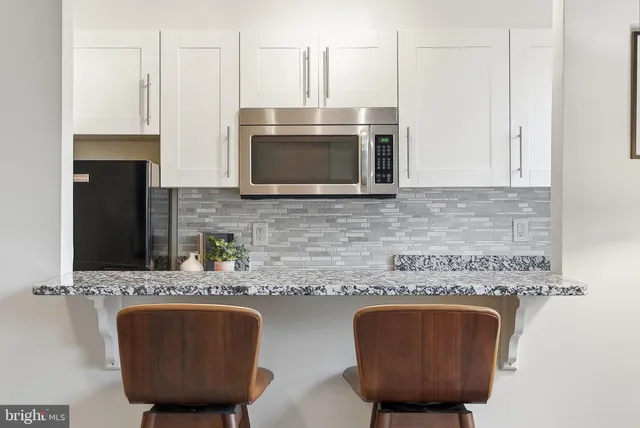 a kitchen with stainless steel appliances granite countertop a sink a microwave cabinets and a wooden floor