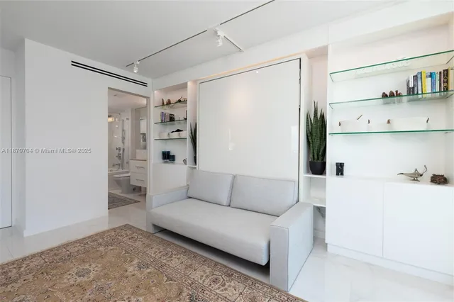 a living room with furniture and a walk in closet with wooden floor