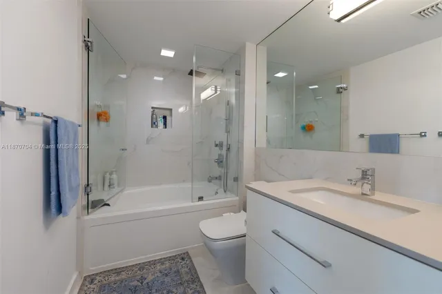 a bathroom with a bathtub shower sink vanity and toilet