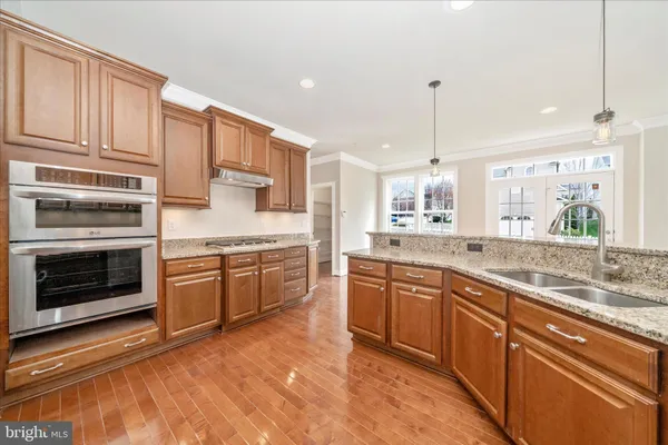 a large kitchen with granite countertop a stove top oven a sink a counter space and cabinets