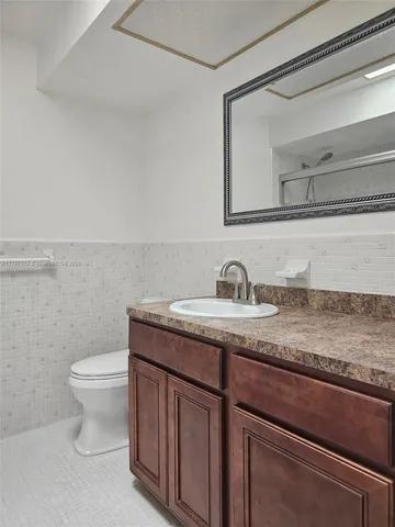 a bathroom with a granite countertop sink a toilet and a mirror