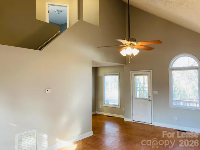 a view of an empty room with window and wooden floor