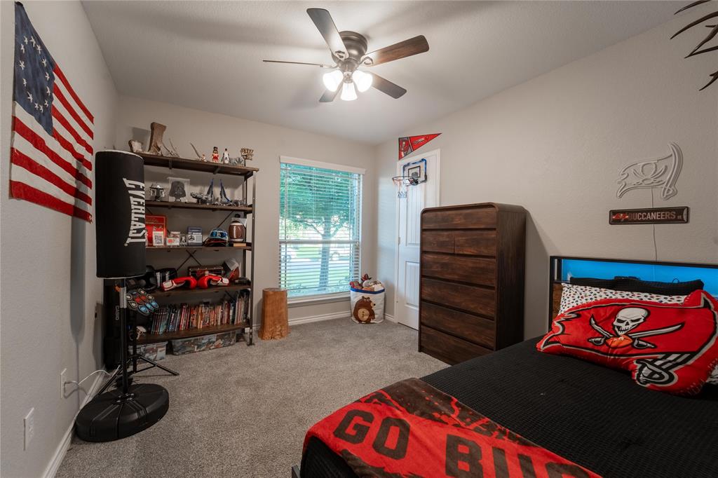5521 Wisdom Court Waco, TX 76708 - Photo 17 of 28 Carpeted room featuring a ceiling fan with integrated lighting, a window with blinds, a built-in shelving unit, a wood-finish dresser, and a white door with a mini basketball hoop
