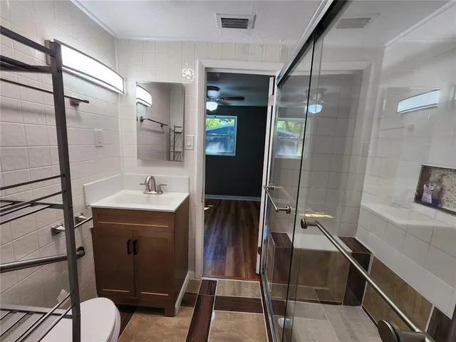 a view of a hallway with bathroom and wooden floor