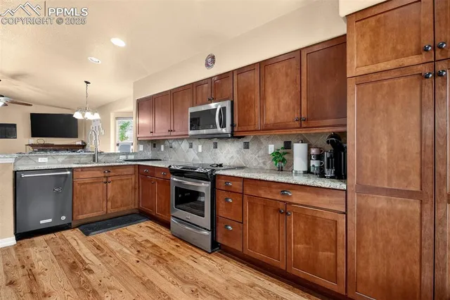 a kitchen with stainless steel appliances granite countertop a refrigerator stove top oven and sink
