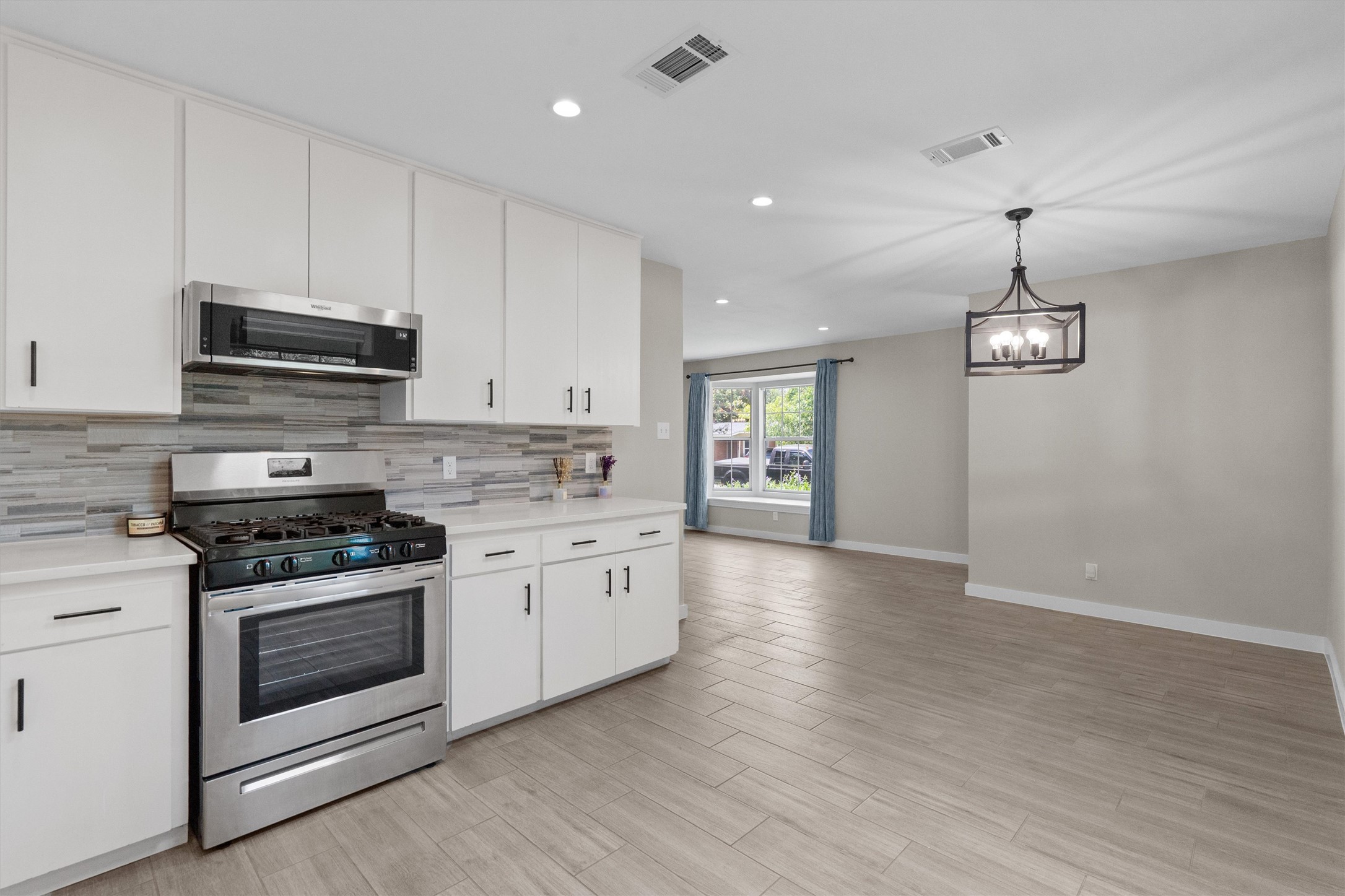 7707 Robalo Road Austin, TX 78757 - Photo 10 of 33 A sleek, modern kitchen with stainless steel appliances seamlessly flows into a well-lit dining area, perfect for entertaining.