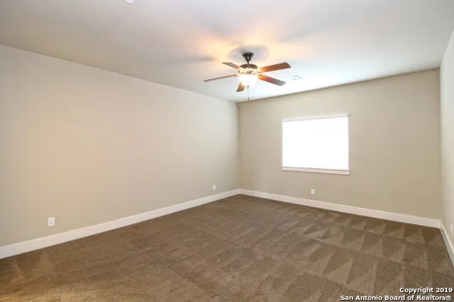 an empty room with a window and a fan
