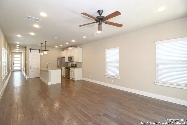 an open kitchen with white cabinets and wooden floor