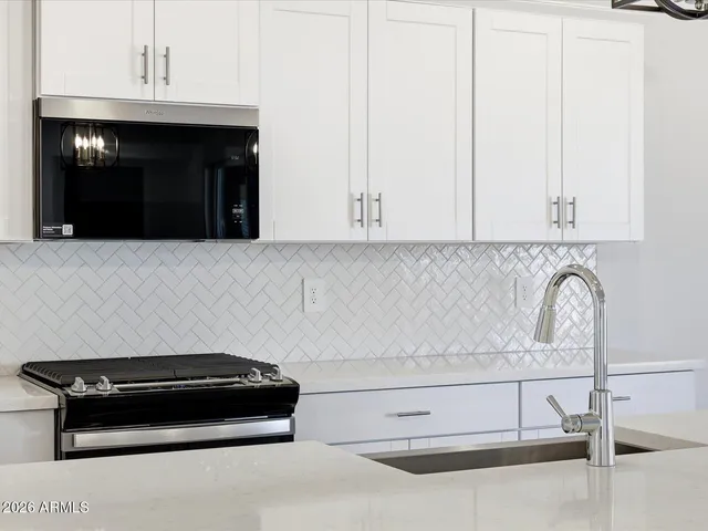 a view of kitchen with stainless steel appliances granite countertop a sink a refrigerator and a stove