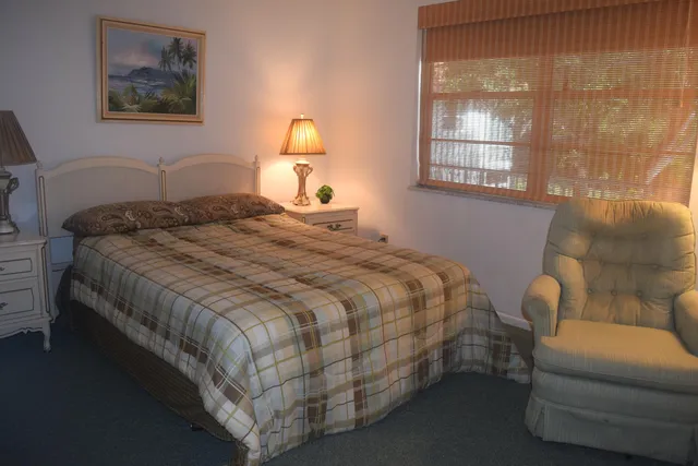a bedroom with a bed and a lamp on dresser
