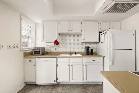 a kitchen with white cabinets sink and refrigerator