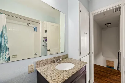 a bathroom with a granite countertop shower sink and mirror