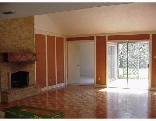 a view of an empty room with wooden floor and a fireplace