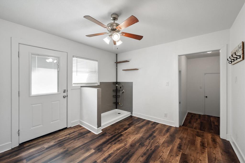 917 Goodwyn Road Italy, TX 76651 - Photo 18 of 40 Wood-finish flooring, ceiling fan with light, tiled shower basin, and white interior paint
